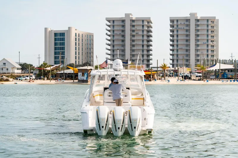 Slide: The Image of 2020 Intrepid 407 Cuddy boat cruising near beachfront buildings and palm trees. - 8
