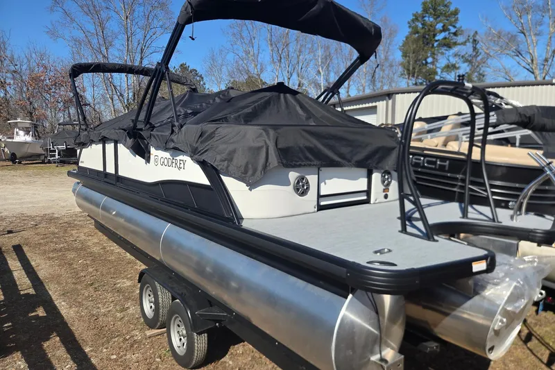 Slide: The Image of 2026 Godfrey Monaco 255 QS pontoon boat on trailer, covered and parked outdoors. - 9