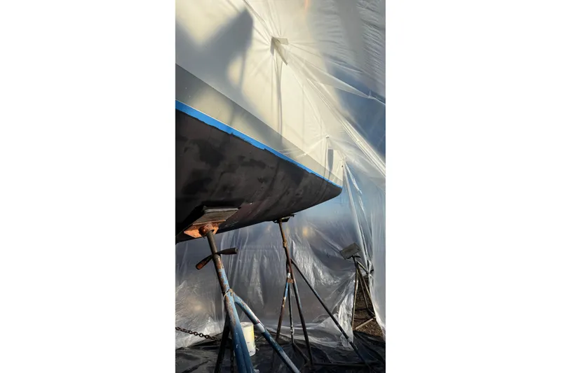 Slide: The Image of 2004 Beneteau First 36.7 sailboat under maintenance, supported by stands, covered in protective plastic. - 32