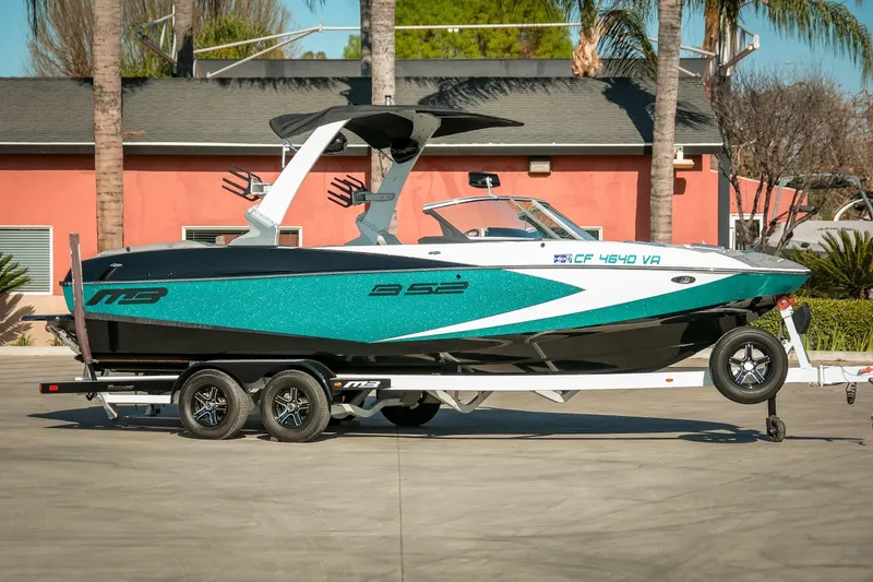 The Image of 2019 MB B52 23 Classic boat on trailer, teal and black design, parked outdoors. - 1
