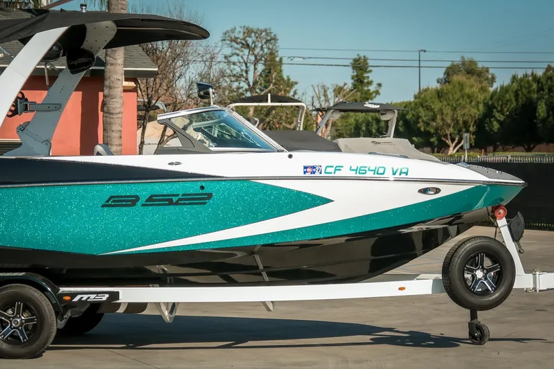Slide: The Image of 2019 MB B52 23 Classic boat on trailer, teal and white design, parked outdoors. - 3