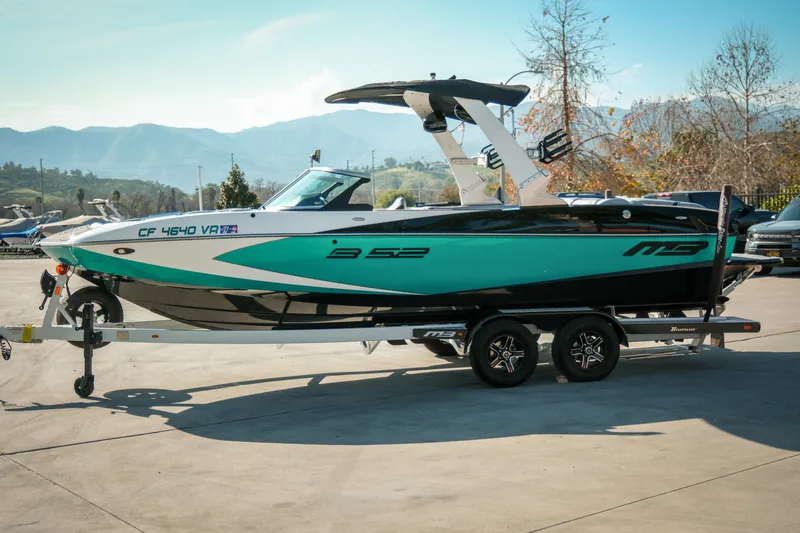 Slide: The Image of 2019 MB B52 23 Classic boat on trailer, parked outdoors with mountains in background. - 6