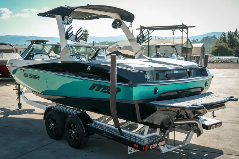 Slide: The Image of 2019 MB B52 23 Classic boat on trailer, teal and black design, parked outdoors. - 7
