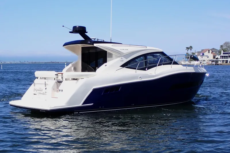 The Image of 2019 Carver C37 Coupe yacht cruising on a sunny day near coastal homes. - 0