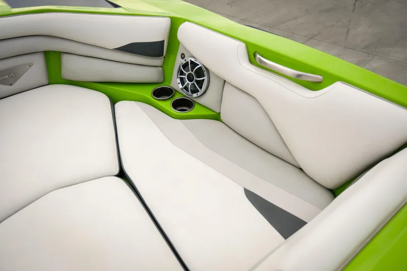 Slide: The Image of 2016 Axis A22 boat interior with green and white seating, speaker, and cup holders. - 12