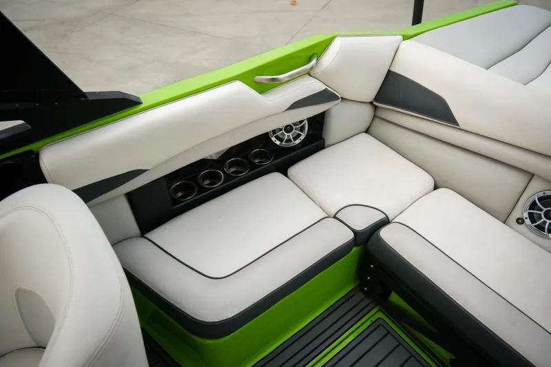 Slide: The Image of 2016 Axis A22 boat interior with white and green seating, cup holders, and speakers. - 15