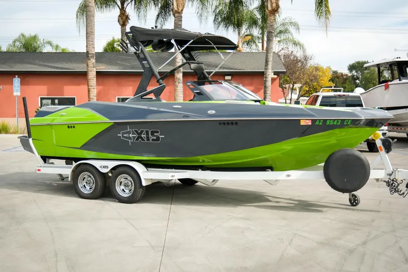 Slide: The Image of 2016 Axis A22 boat in green and black on a trailer, parked outdoors. - 26