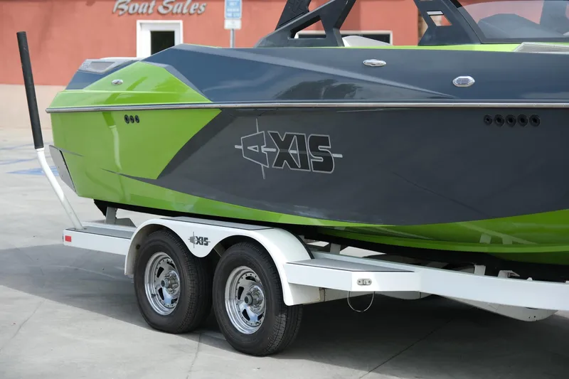Slide: The Image of 2016 Axis A22 boat on trailer at dealership, featuring green and gray design. - 27