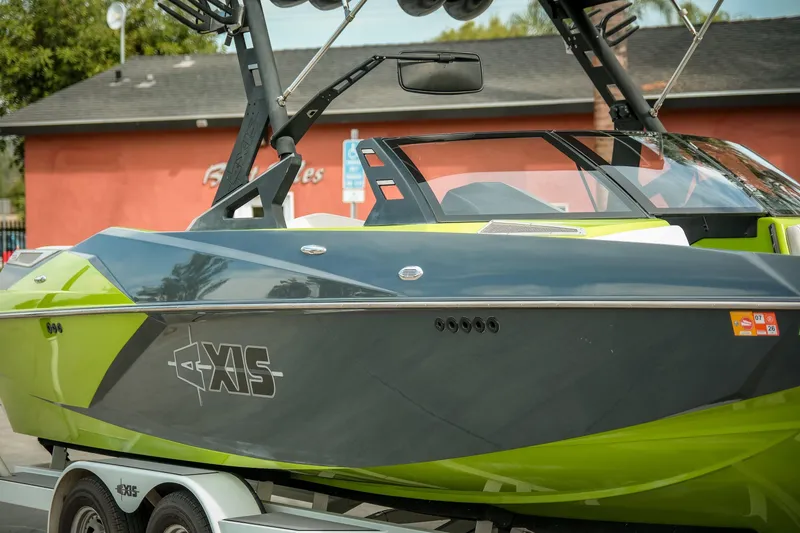 Slide: The Image of 2016 Axis A22 boat with vibrant green and black design on a trailer. - 28