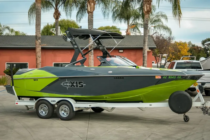 Slide: The Image of 2016 Axis A22 boat in green and black on a trailer, parked outdoors. - 3