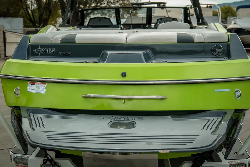 Slide: The Image of 2016 Axis A22 boat, vibrant green rear view, featuring swim platform and seating. - 4