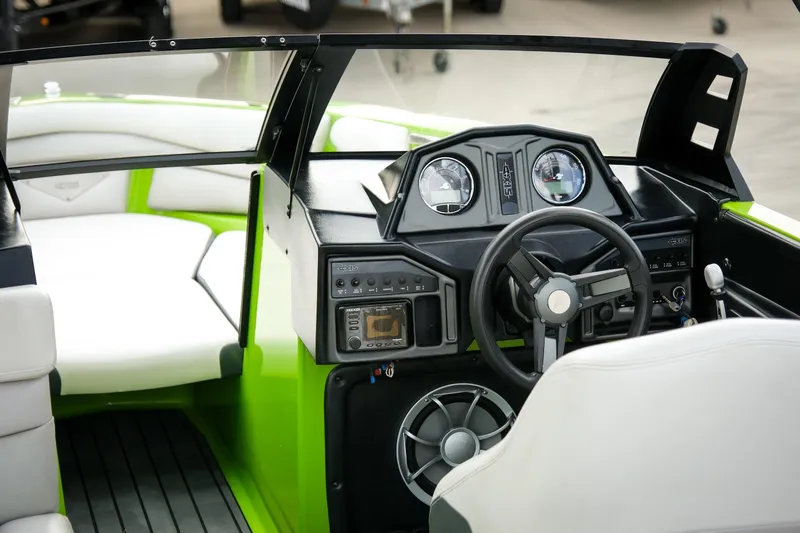 Slide: The Image of 2016 Axis A22 boat interior with steering wheel and dashboard, featuring green and white seating. - 8