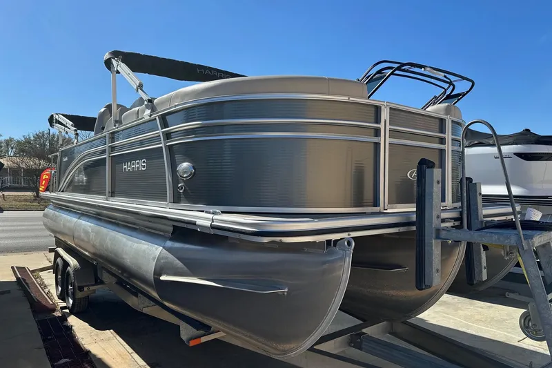 The Image of 2019 Harris Cruiser 230 pontoon boat on trailer under clear blue sky. - 0