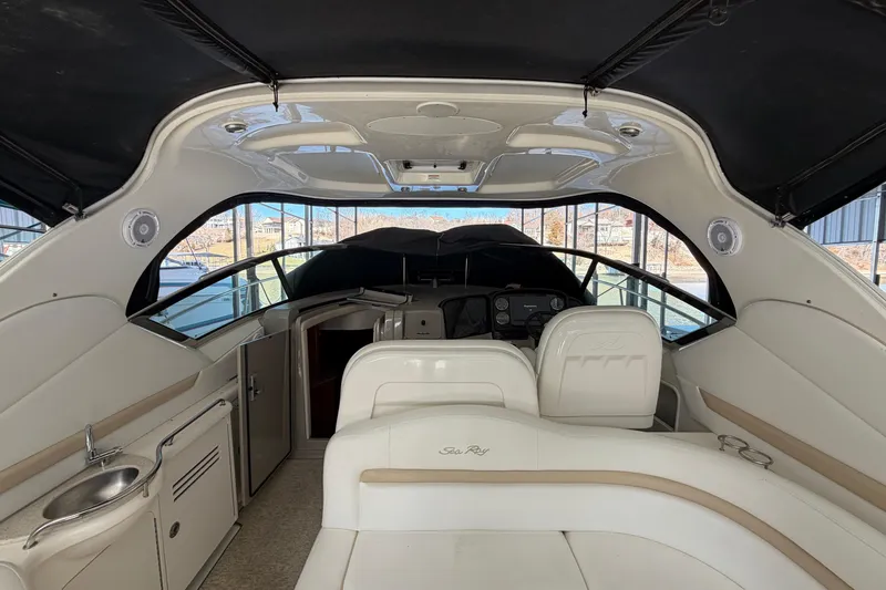 Slide: The Image of 2008 Sea Ray 38 Sundancer interior with seating, helm, and kitchenette under black canopy. - 10