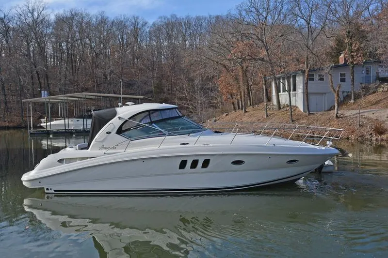 Slide: The Image of 2008 Sea Ray 38 Sundancer yacht cruising on a calm lake with forested background. - 2