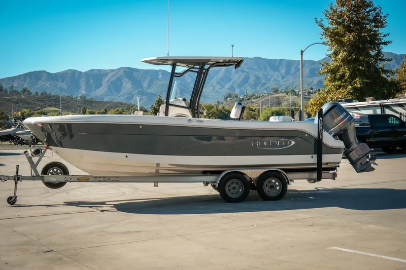 The Image of 2020 Robalo R242 Center Console boat on trailer, scenic mountain backdrop. - 1