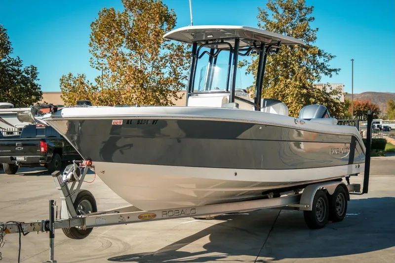 Slide: The Image of 2020 Robalo R242 Center Console boat on trailer, parked outdoors. - 2