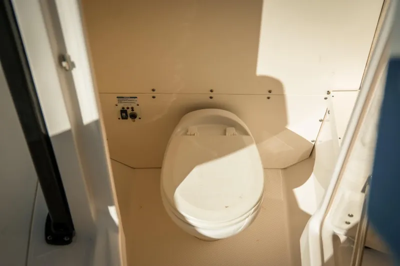 Slide: The Image of 2020 Robalo R242 Center Console boat interior with a compact marine toilet. - 22