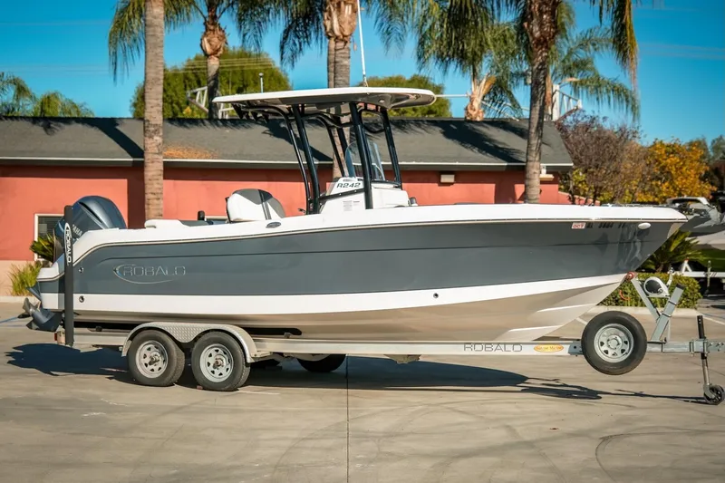 Slide: The Image of 2020 Robalo R242 Center Console boat on trailer, parked outdoors with palm trees. - 5