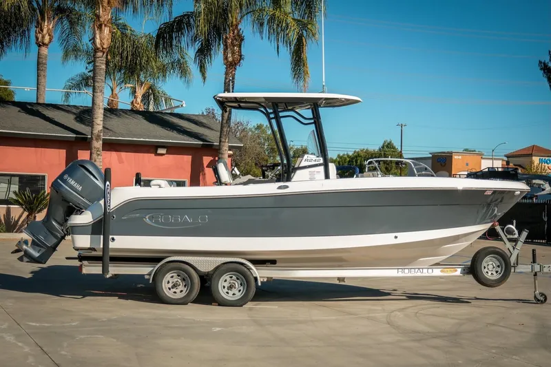 Slide: The Image of 2020 Robalo R242 Center Console boat on trailer, parked outdoors with palm trees. - 7