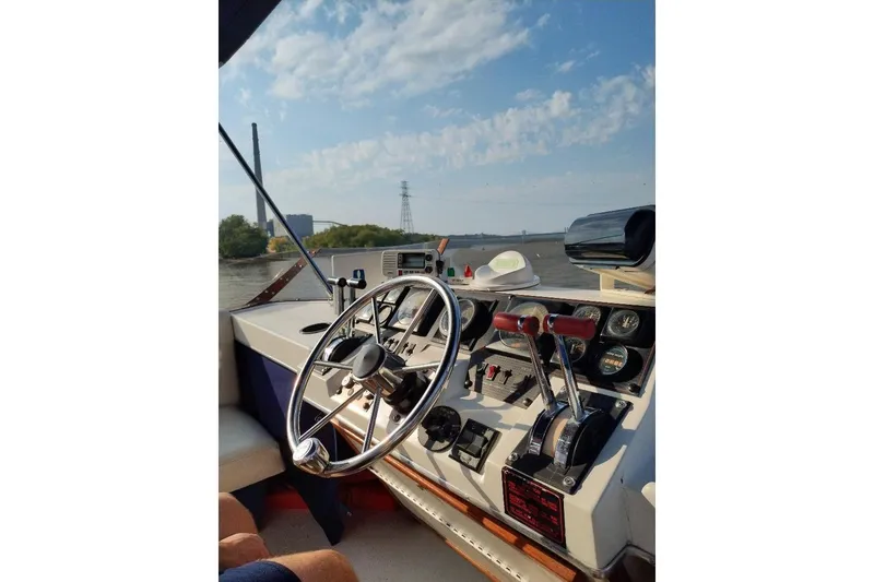 Slide: The Image of 1989 Bayliner 3888 Motoryacht helm with steering wheel and controls, cruising on a sunny day. - 32