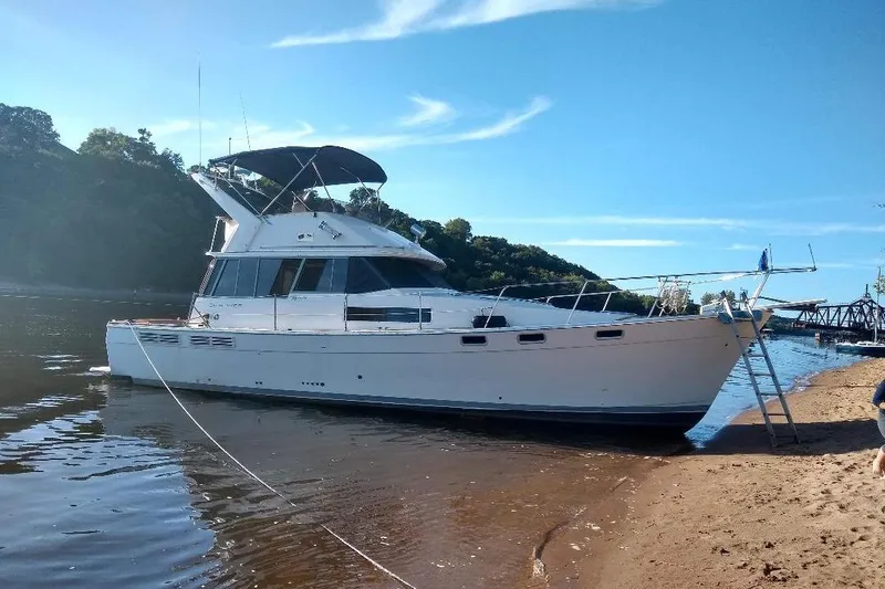 Slide: The Image of 1989 Bayliner 3888 Motoryacht docked on sandy shore under clear blue sky. - 35