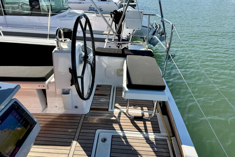 Slide: The Image of 2019 Beneteau Oceanis 41.1 yacht cockpit with steering wheel and seating, docked on calm water. - 20