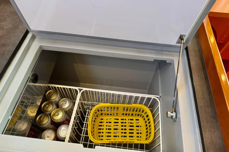 Slide: The Image of Open fridge on Beneteau Oceanis 41.1 yacht, showing canned drinks and a yellow basket. - 33