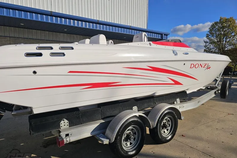 Slide: The Image of 2008 Donzi 27 ZR speedboat with red accents on a trailer, parked outdoors. - 11