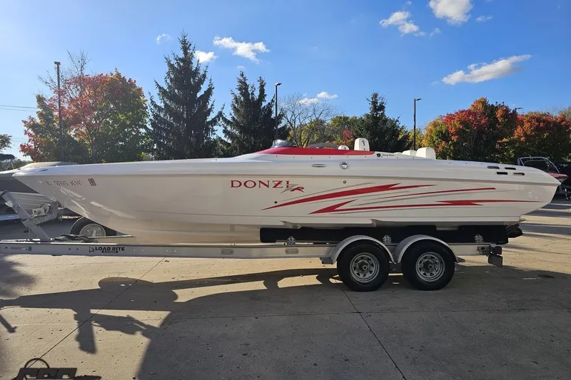 Slide: The Image of 2008 Donzi 27 ZR speedboat on trailer, white with red accents, parked outdoors. - 25