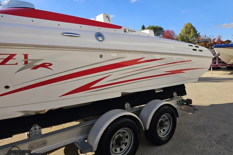 Slide: The Image of 2008 Donzi 27 ZR boat with red graphics on a trailer, under clear blue sky. - 27