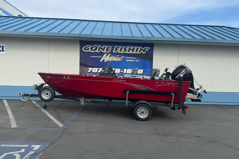 The Image of 2021 Lund 1650 Angler SS boat on trailer, parked outside a fishing store. - 1