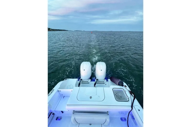 Slide: The Image of 2024 Sea Hunt Gamefish 25 boat with dual engines, illuminated deck, and storage compartments. - 2