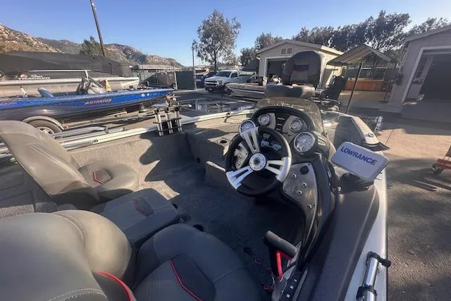Slide: The Image of 2022 Tracker Pro Team 175 TXW boat interior with steering wheel and dashboard, parked outdoors. - 4