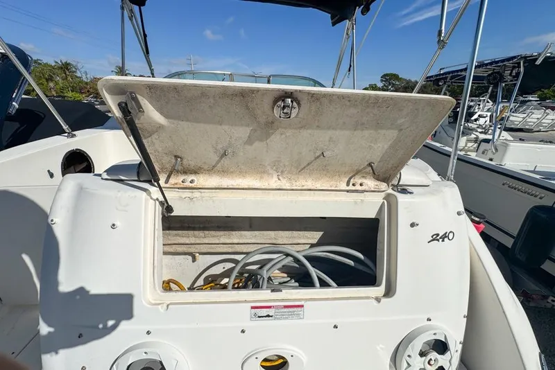 Slide: The Image of 2007 Sea Ray 240 Sundancer boat storage compartment with open lid and visible hoses. - 127
