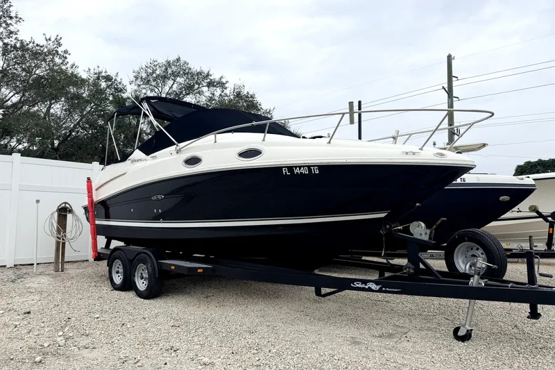 Slide: The Image of 2007 Sea Ray 240 Sundancer boat on trailer, black and white exterior, parked outdoors. - 2