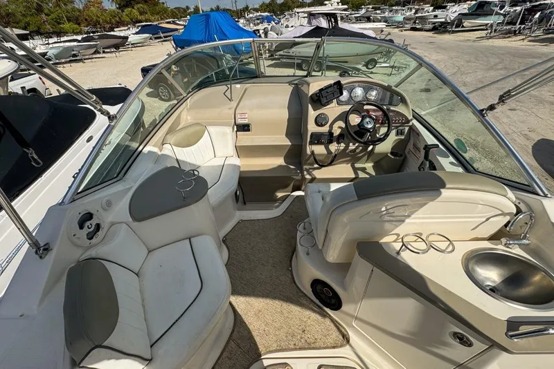 Slide: The Image of 2007 Sea Ray 240 Sundancer boat interior with helm, seating, and sink in a marina setting. - 23