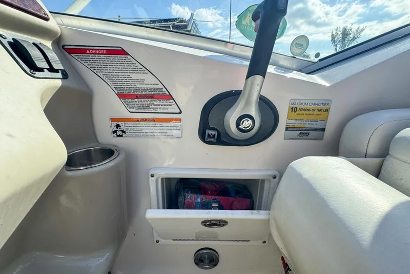 Slide: The Image of 2007 Sea Ray 240 Sundancer helm with steering wheel, warning labels, and storage compartment. - 40