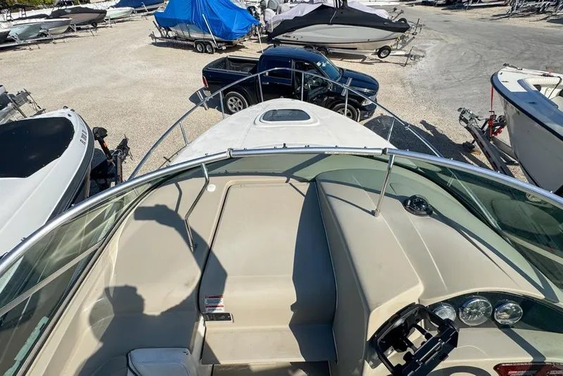 Slide: The Image of 2007 Sea Ray 240 Sundancer boat interior with dashboard and seating, parked in a marina. - 49