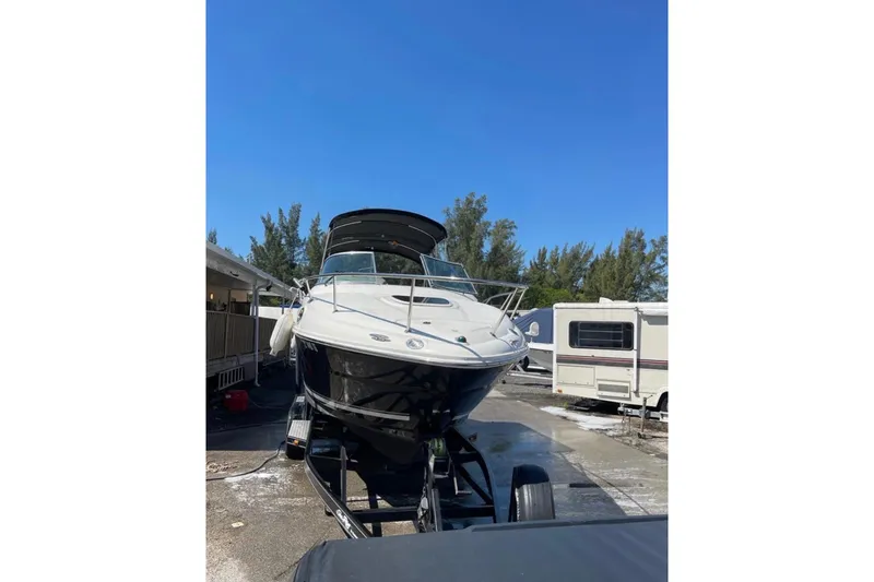 Slide: The Image of 2007 Sea Ray 240 Sundancer boat on trailer, parked outdoors near white fence. - 5