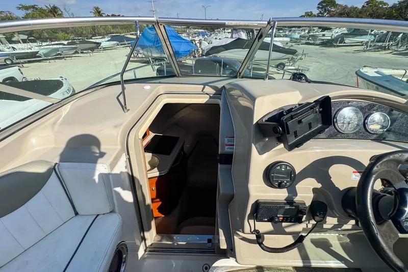 Slide: The Image of 2007 Sea Ray 240 Sundancer cockpit with steering wheel, controls, and cabin entrance. - 55