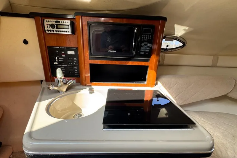 Slide: The Image of 2007 Sea Ray 240 Sundancer cabin kitchenette with sink, microwave, and control panel. - 65