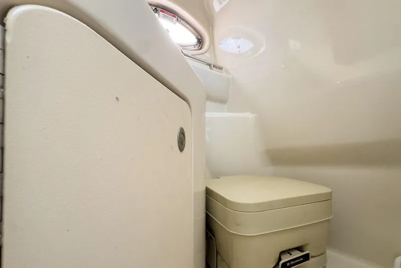 Slide: The Image of 2007 Sea Ray 240 Sundancer cabin bathroom with compact toilet and storage. - 81