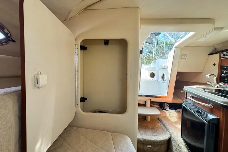 Slide: The Image of Interior of 2007 Sea Ray 240 Sundancer boat, featuring kitchenette and open storage compartment. - 92