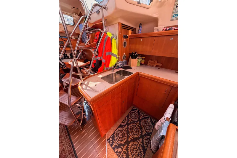 Slide: The Image of Interior of 2005 Hunter Passage 456 yacht, featuring a compact kitchen with wooden cabinetry. - 36