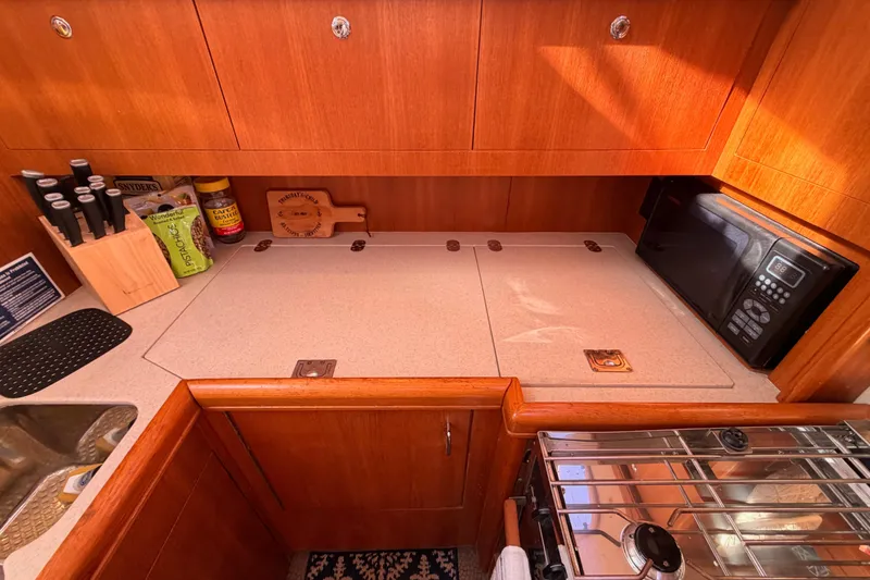 Slide: The Image of Galley kitchen in 2005 Hunter Passage 456 yacht with microwave and wooden cabinetry. - 37
