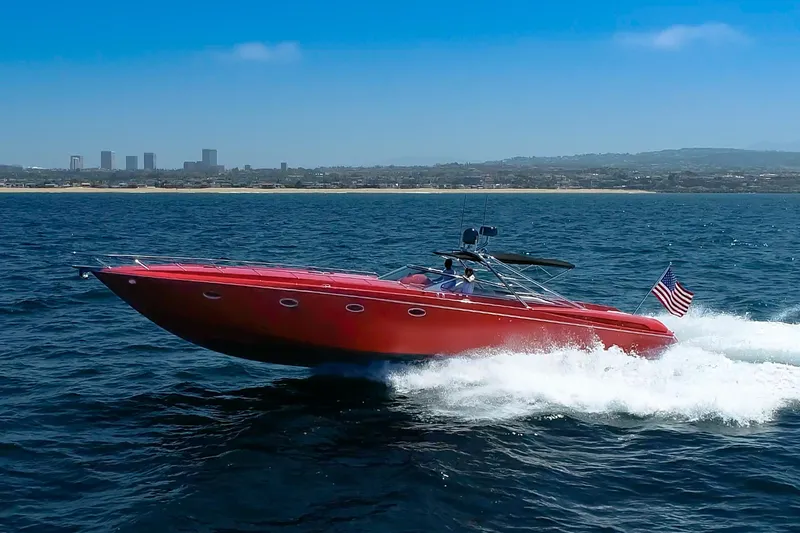 The Image of 2002 Hallett Custom High Performance Express Cruiser speeding on ocean with city skyline backdrop. - 0