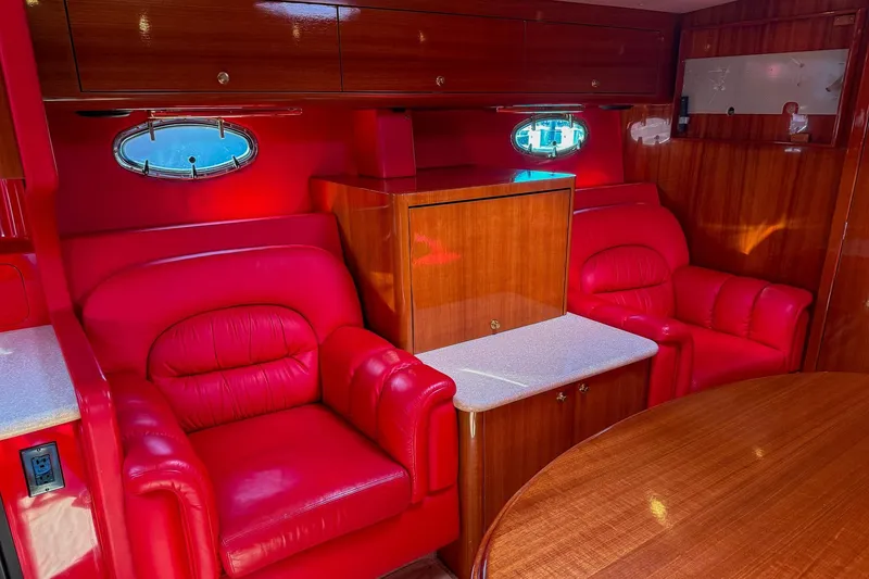 Slide: The Image of Luxurious red leather seating in 2002 Hallett Express Cruiser interior, featuring wood accents and porthole windows. - 8