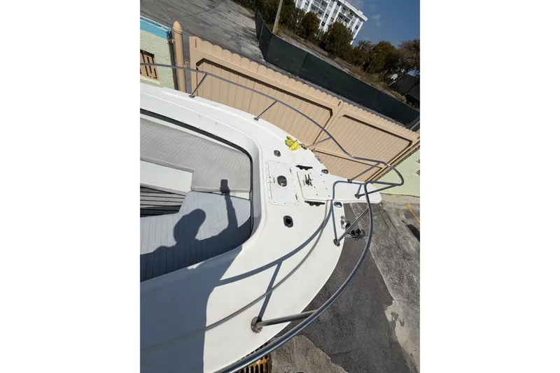 Slide: The Image of 1997 Dusky 256 CC boat deck with railing and shadow, parked near a fence. - 22