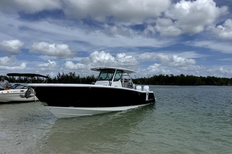 The Image of 2026 Blackfin 332 CC boat anchored in shallow water under a cloudy sky. - 0